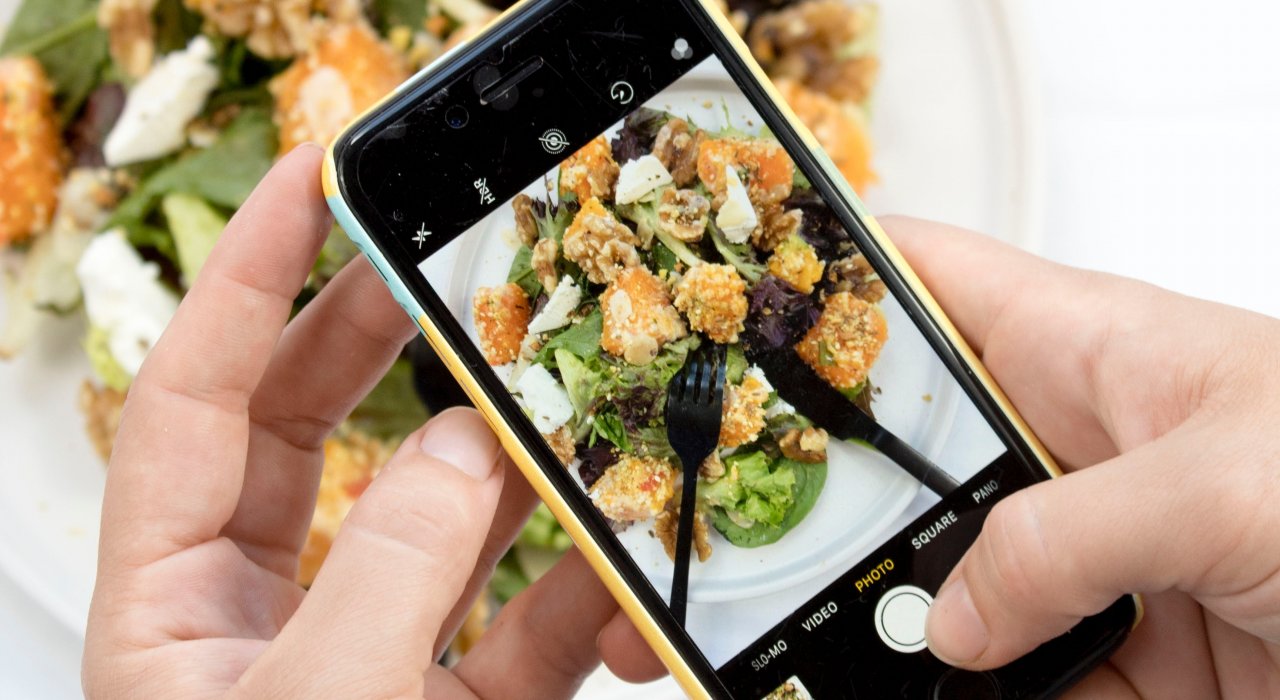 Eine Person fotografiert eine Mahlzeit mit einem Smartphone